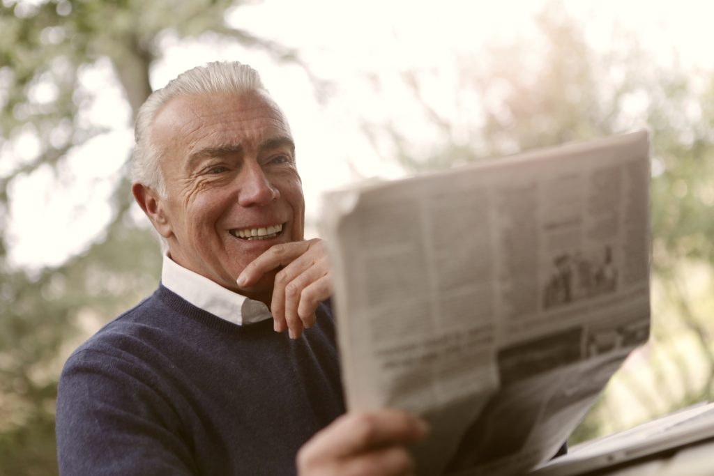 senior man reading newspaper with smile