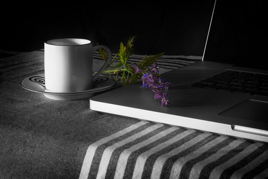 mug and laptop with flowers on table